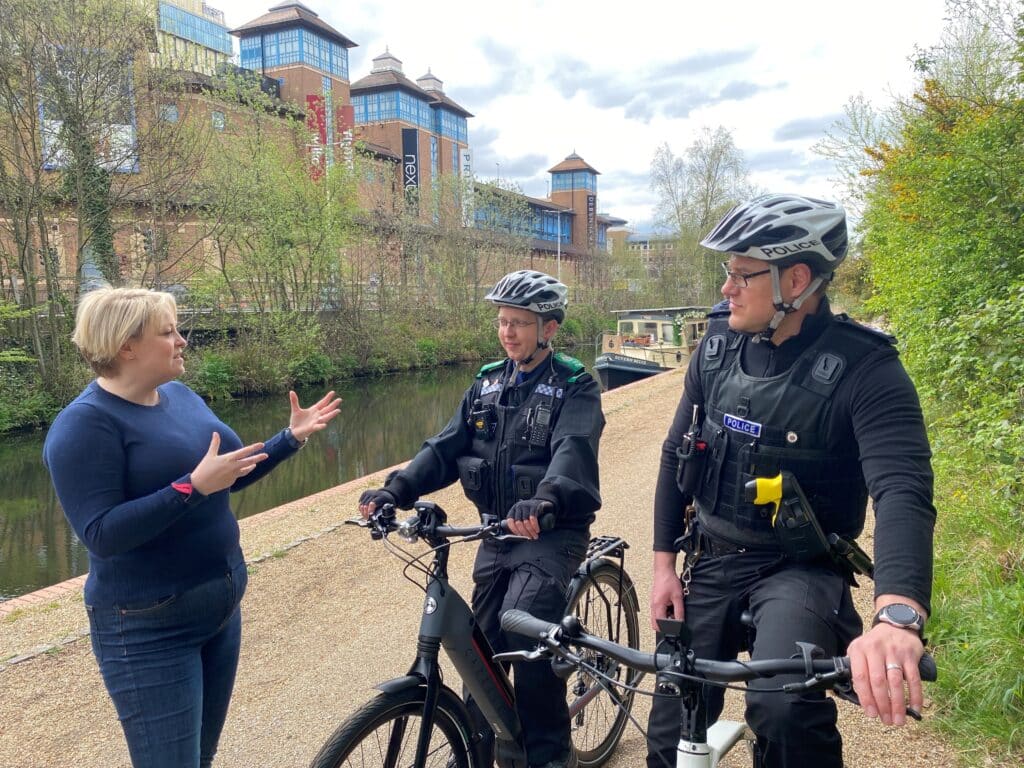 A Cummissaria Lisa Townsend cù l'ufficiali di Pulizia di Surrey nantu à e biciclette elettriche longu u Canale di Woking in un ghjornu assulanatu