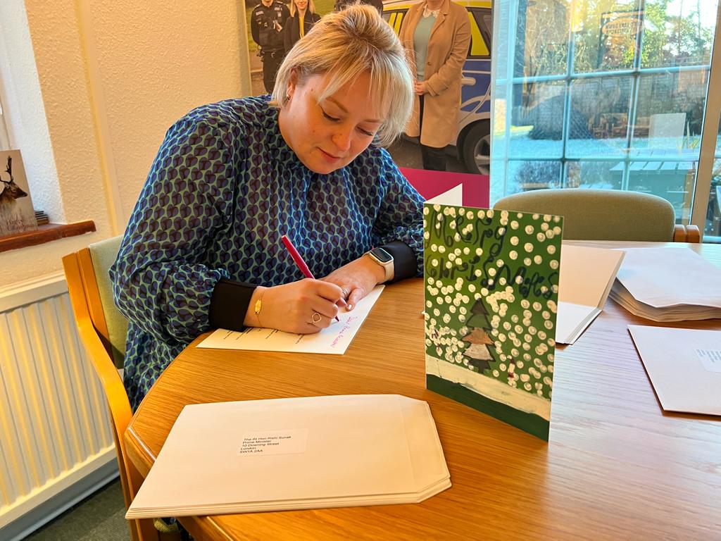 Police and Crime Commissioner Lisa Townsend signs Christmas cards designed by a young person in her office at Surrey Police HQ