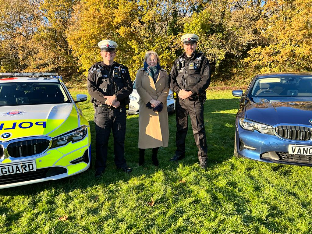 Police and Commissioner Lisa Townsend with Surrey Police officers from the fatal five team standing between police cars on sunny day