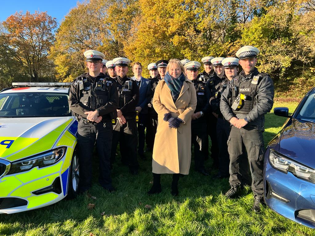 Politie- en misdaadcommissaris Lisa Townsend op een zonnige foto met verschillende politieagenten en twee politievoertuigen die deel uitmaken van het verkeersveiligheidsteam van Surrey Police Vanguard, opgericht in 2022