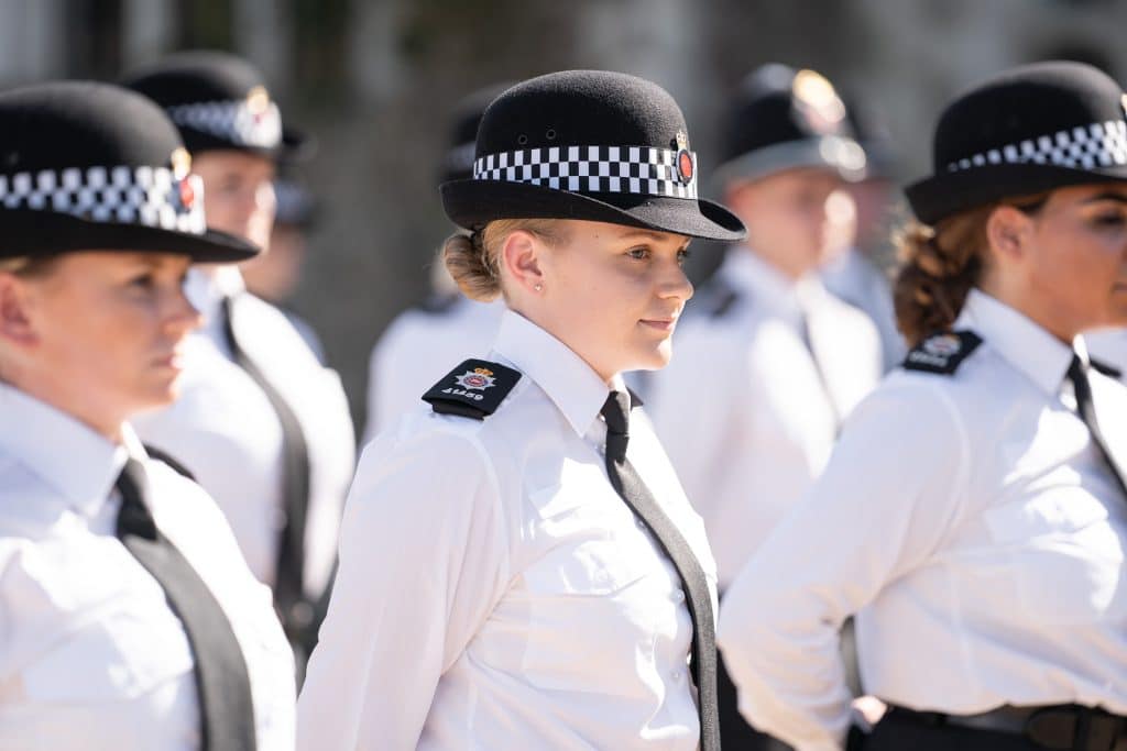 New Surrey Police officers with young female officer in smart uniform centre shot during their passing out parade. 