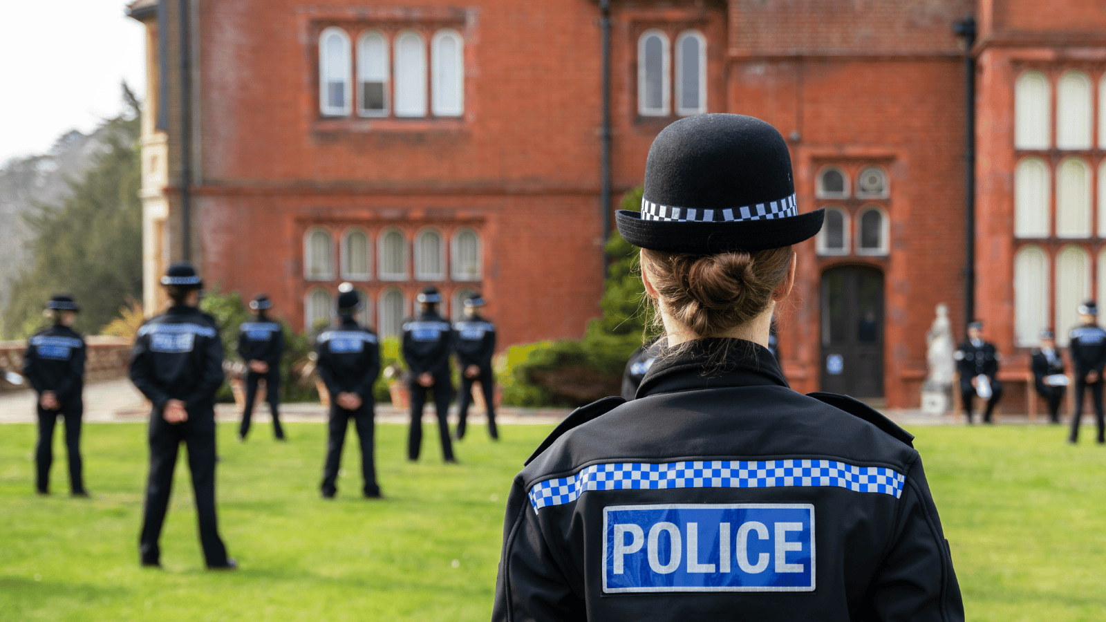 γυναίκα αστυνομικός με καπέλο στο προσκήνιο μιας φωτογραφίας νέων αστυνομικών που στέκονται στο προσκήνιο στο αρχηγείο της αστυνομίας του Surrey