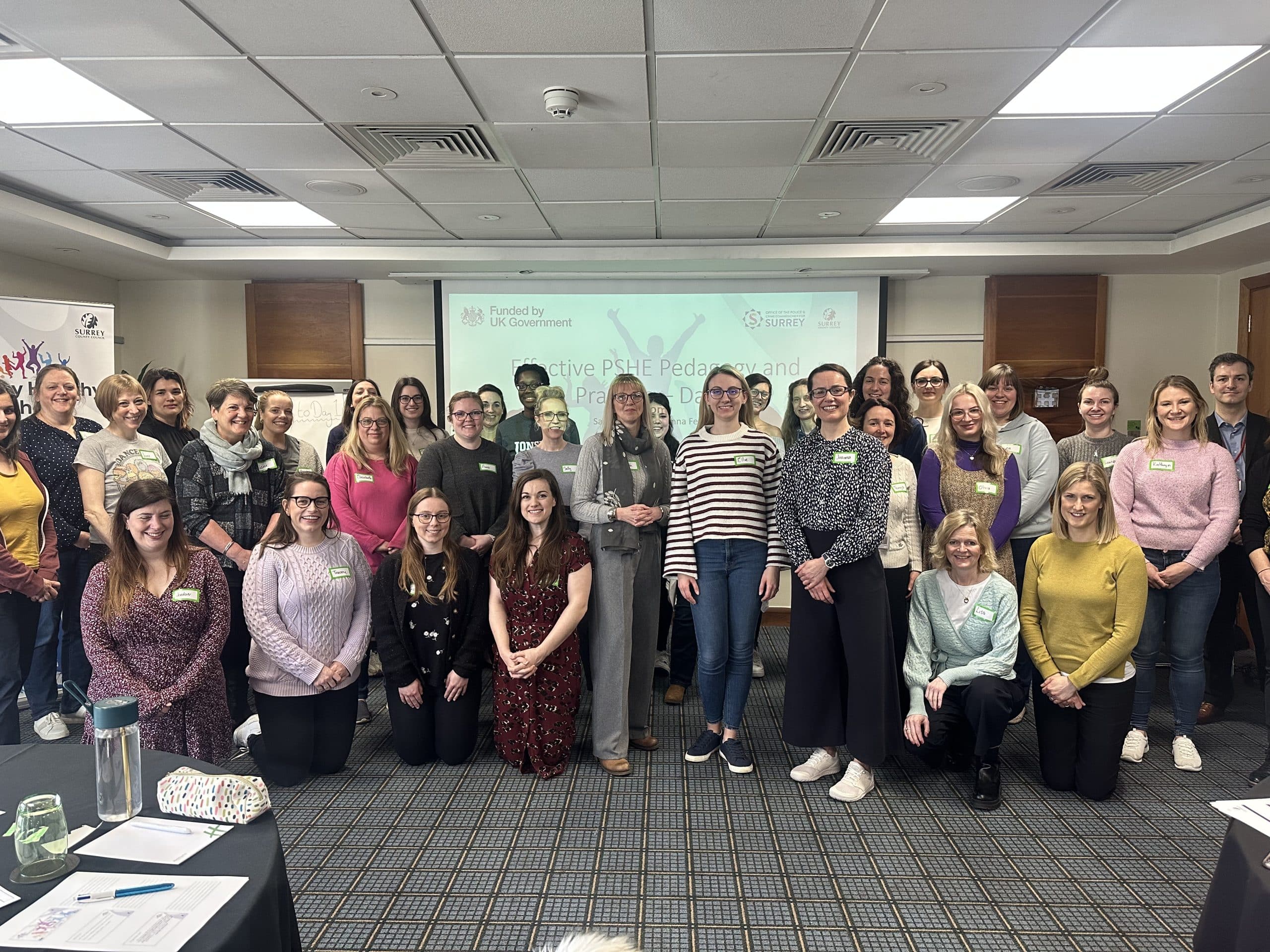 group photo of 27 Surrey teachers and staff of the Office of the Police and Crime Commissioner for Surrey in a training room, after almost one million pounds in funding is provided to provide bespoke training and a campaign to educate children and young people about violence against women and girls