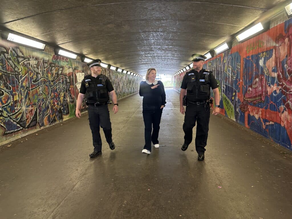 Police and Crime Commissioner walking through graffiti covered tunnel with two male police officers from the local team tackling anti-social behaviour in Spelthorne