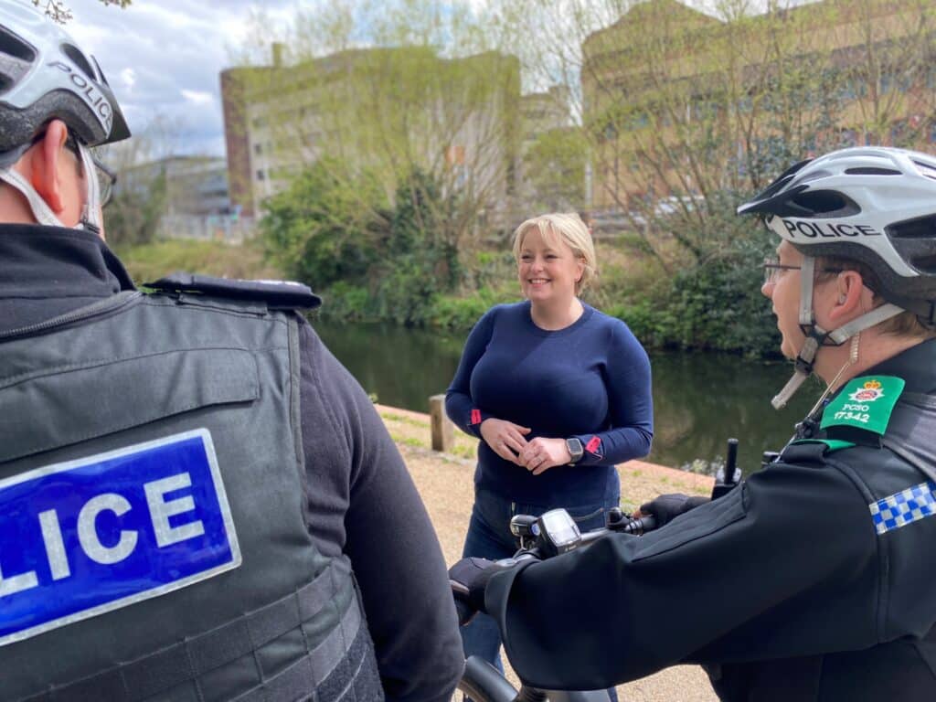 Sunny photo of Police and Crime Commissioner Lisa Townsend speaking to local Surrey Police officers on their bikes on the Woking canal path