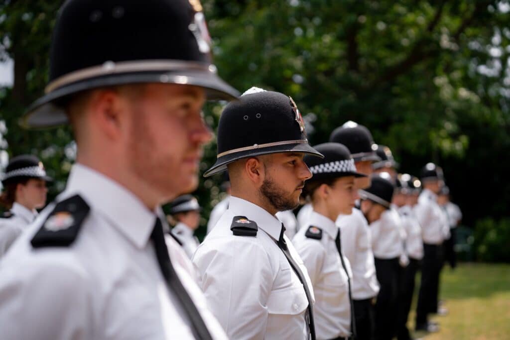 Gli agenti di polizia del Surrey appena reclutati in uniforme formale si sono messi in fila per l'ispezione al loro attestato