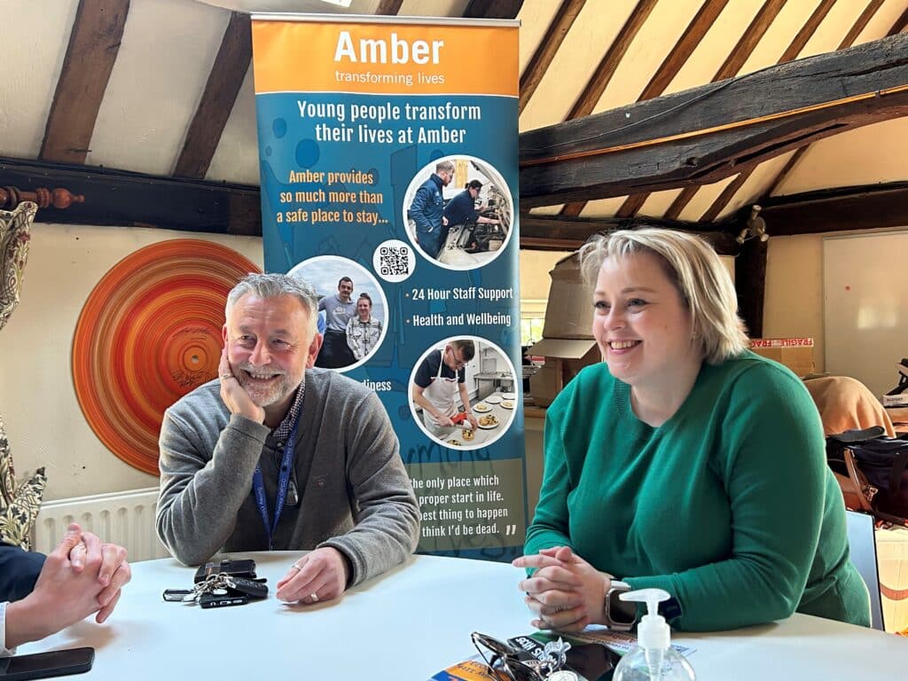 Police and Crime Commissioner Lisa Townsend sitting with a member of her team in front of the Amber charity sign
