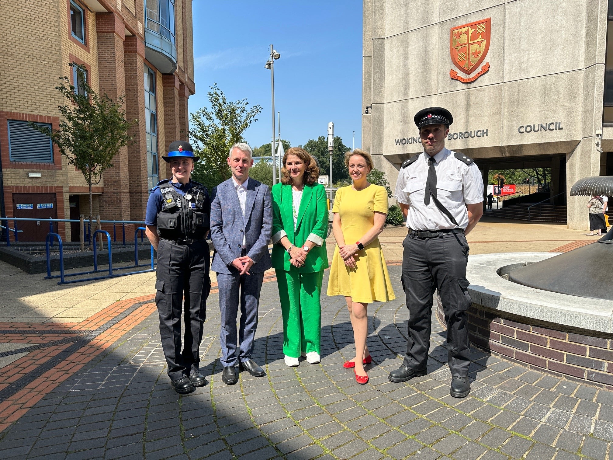 The image shows PCSO Becca Bullock, Woking MP Will Forster, Dame Diana Johnson, Surrey Police and Crime Commissioner Lisa Townsend, and Woking Borough Commander Inspector Ed Lyons standing in Woking town centre. Everyone is looking forwards and smiling in the posed shot.