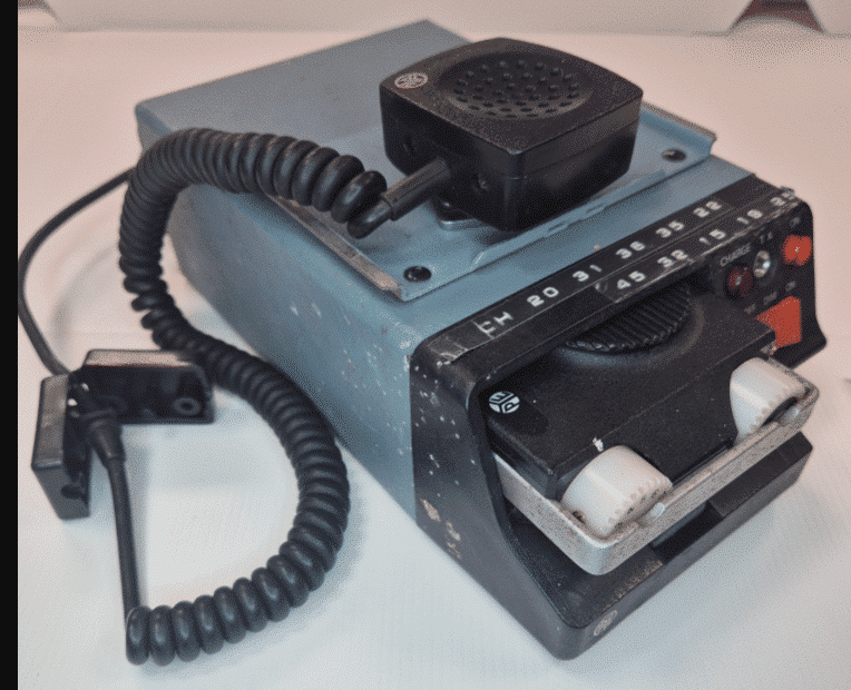 Picture shows a pale blue oblong device  - there are channel numbers listed along the front on laminated sticky tape.  And there are a couple fo input points at the front and a red switch.  The PYE lo and brand name is also on the front of the device in white. On top of the blue device is a black receiver that is connected to the device by a curly black cord with a clip.
